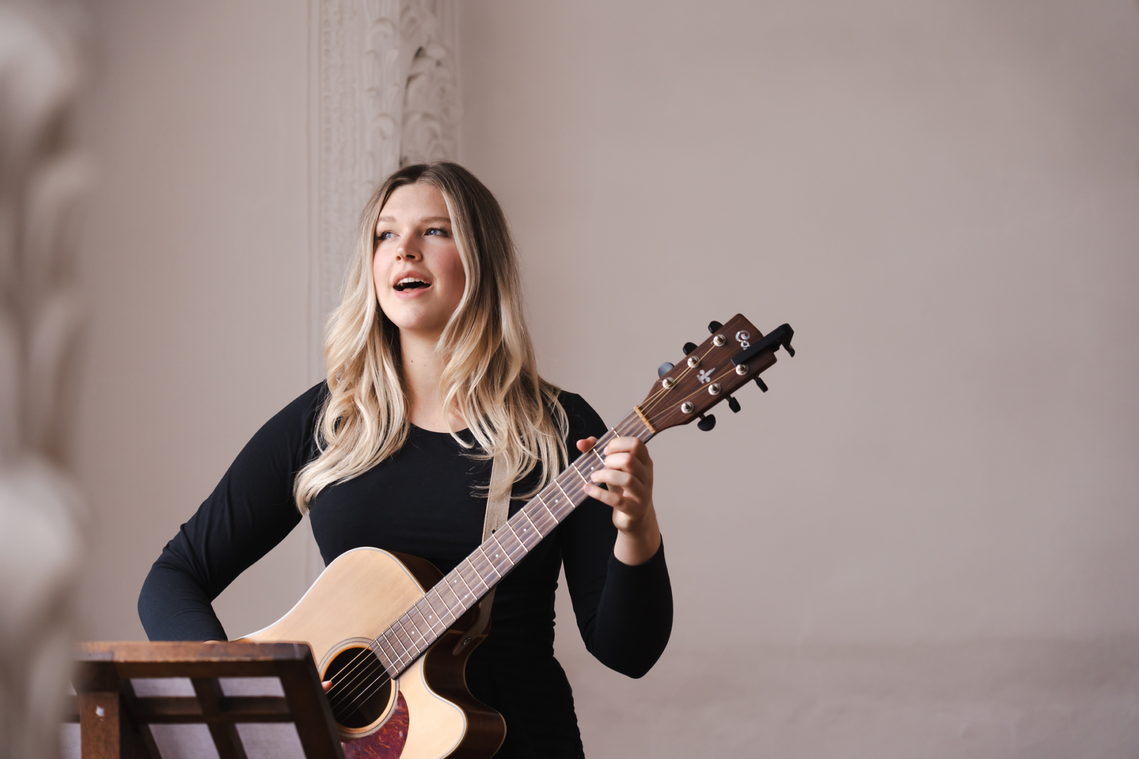 Lena Opitz Sologesang - Lena Opitz steht, in schwarz gekleidet und singt mit einer Gitarre vor dem Körper